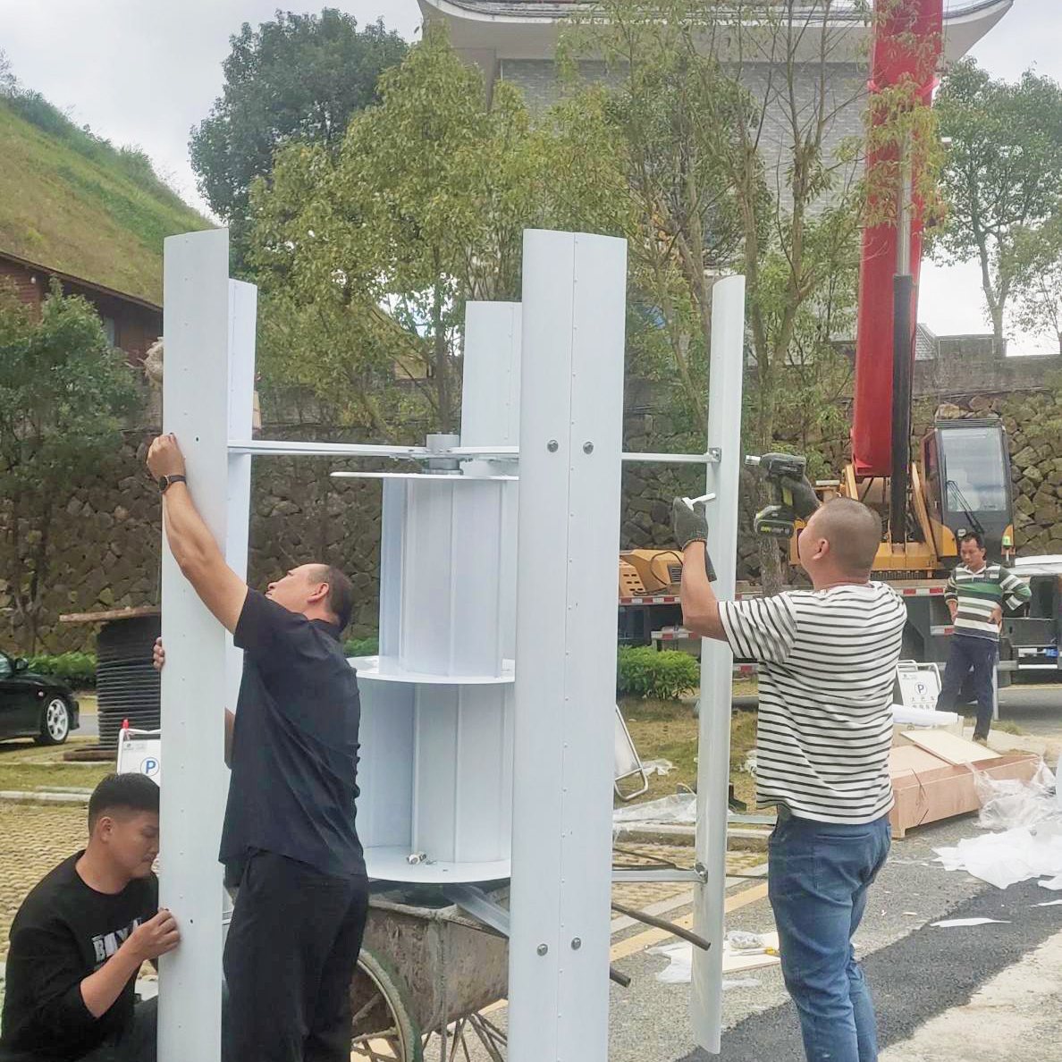 Installers fitting the upright blades of an H series vertical wind turbine during assembly