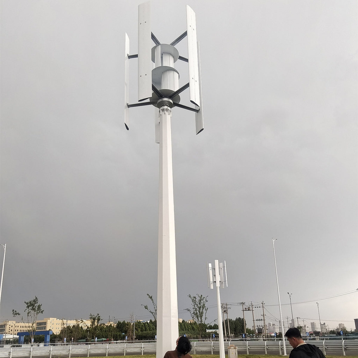 H1000 vertical wind turbine on a tall roadside mast with installers at its base