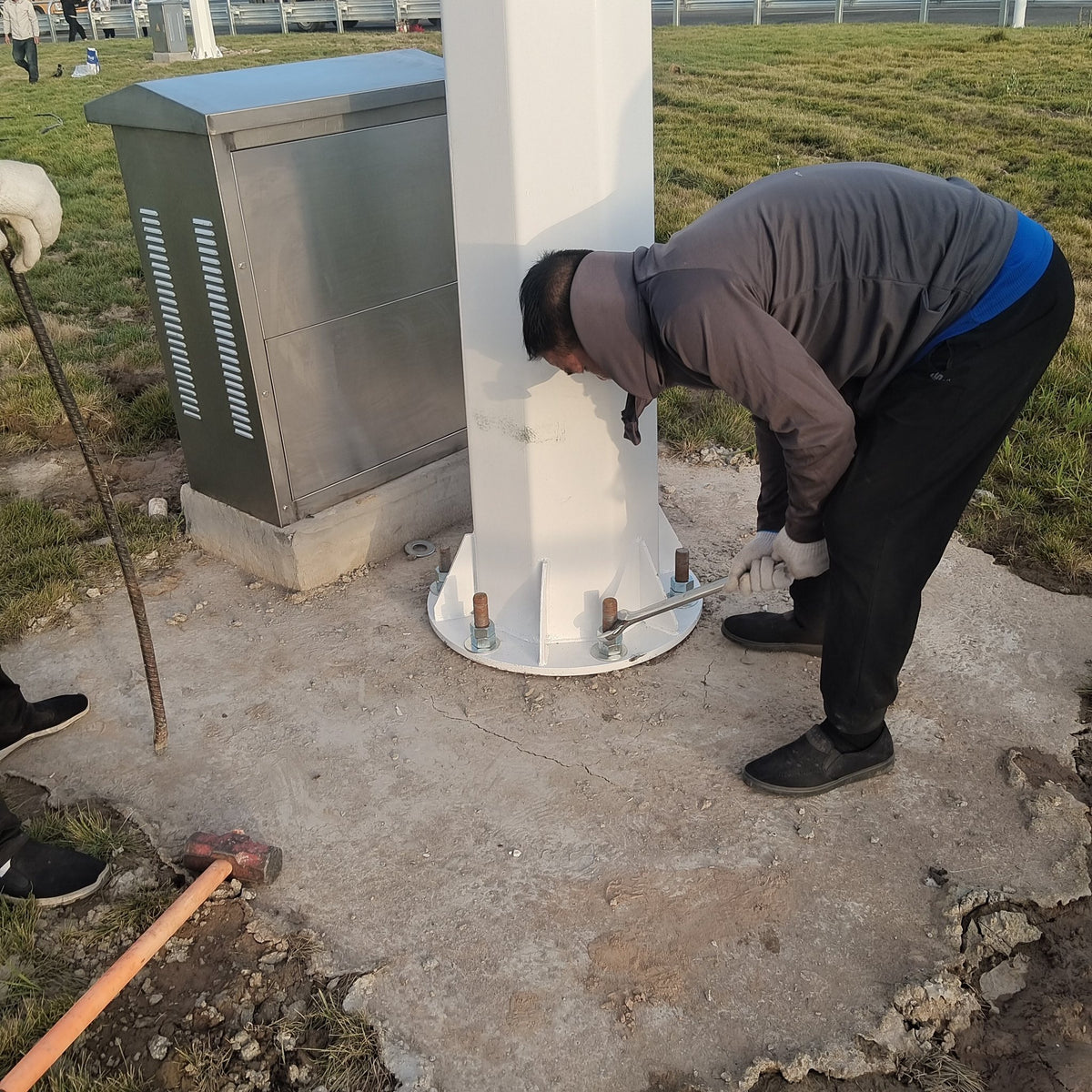 Installer bolting the base flange of an H series turbine mast to its concrete footing