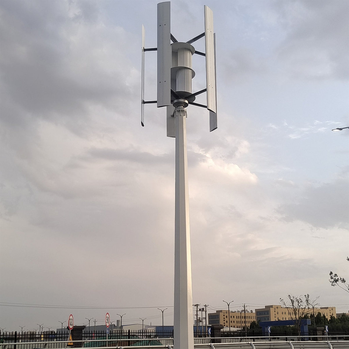 H1000 vertical wind turbine on a tall mast with a ground-level equipment cabinet at its base