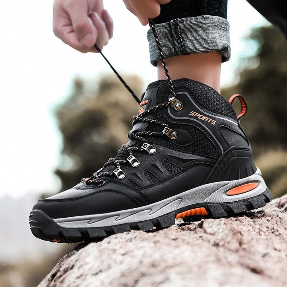 Black hiking boot on a rock while the wearer pulls the laces tight