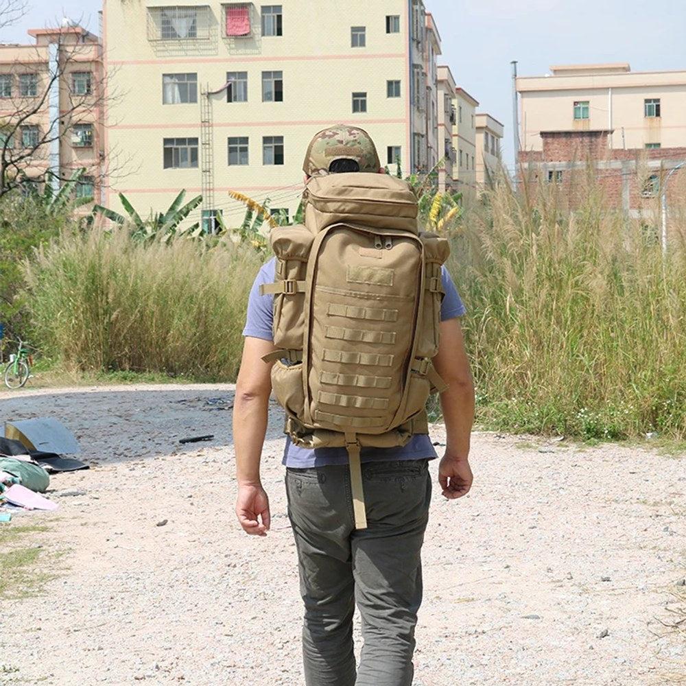 Man walking down a gravel track wearing the tan tactical backpack