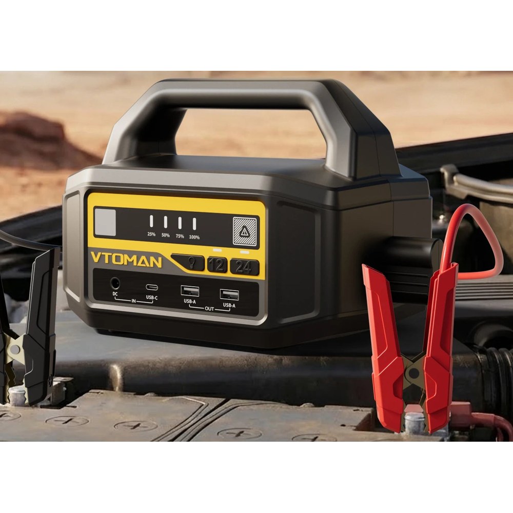 VTOMAN V-Truck jump starter with clamps connected to a vehicle battery in an engine bay