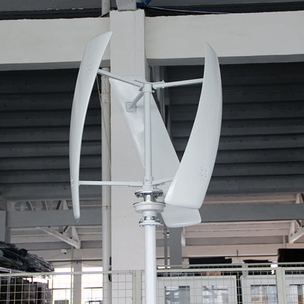 White three-blade X-series vertical-axis turbine test-mounted on a pole inside the factory, steel roof trusses behind - representative X-series photo.