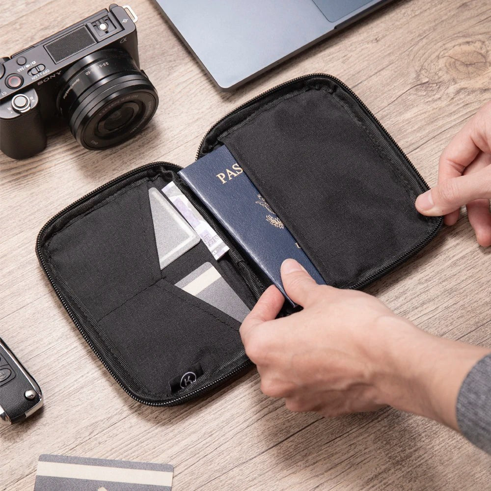 Hand sliding a passport into the open pouch next to the card pockets