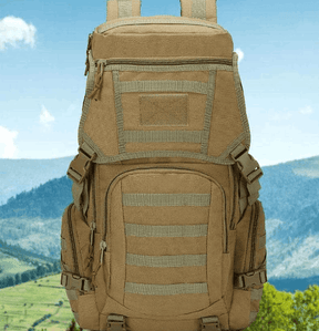 Khaki daypack front-on showing top lid and patch panel, mountain backdrop