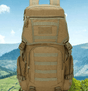 Khaki daypack front-on showing top lid and patch panel, mountain backdrop