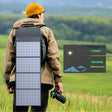 Hiker with a camera, the folded panel strapped down the back of a pack in open grassland