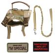 Camo vest harness with its rubber grab handle and D-ring, shown with the bungee lead and two morale patches