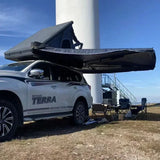 Awning half deployed beside a rooftop tent on a white four-wheel drive