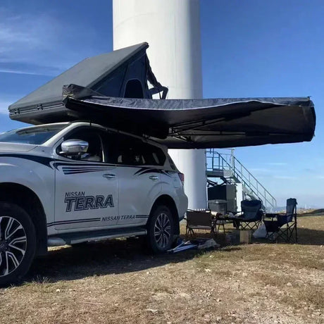 Awning half deployed beside a rooftop tent on a white four-wheel drive
