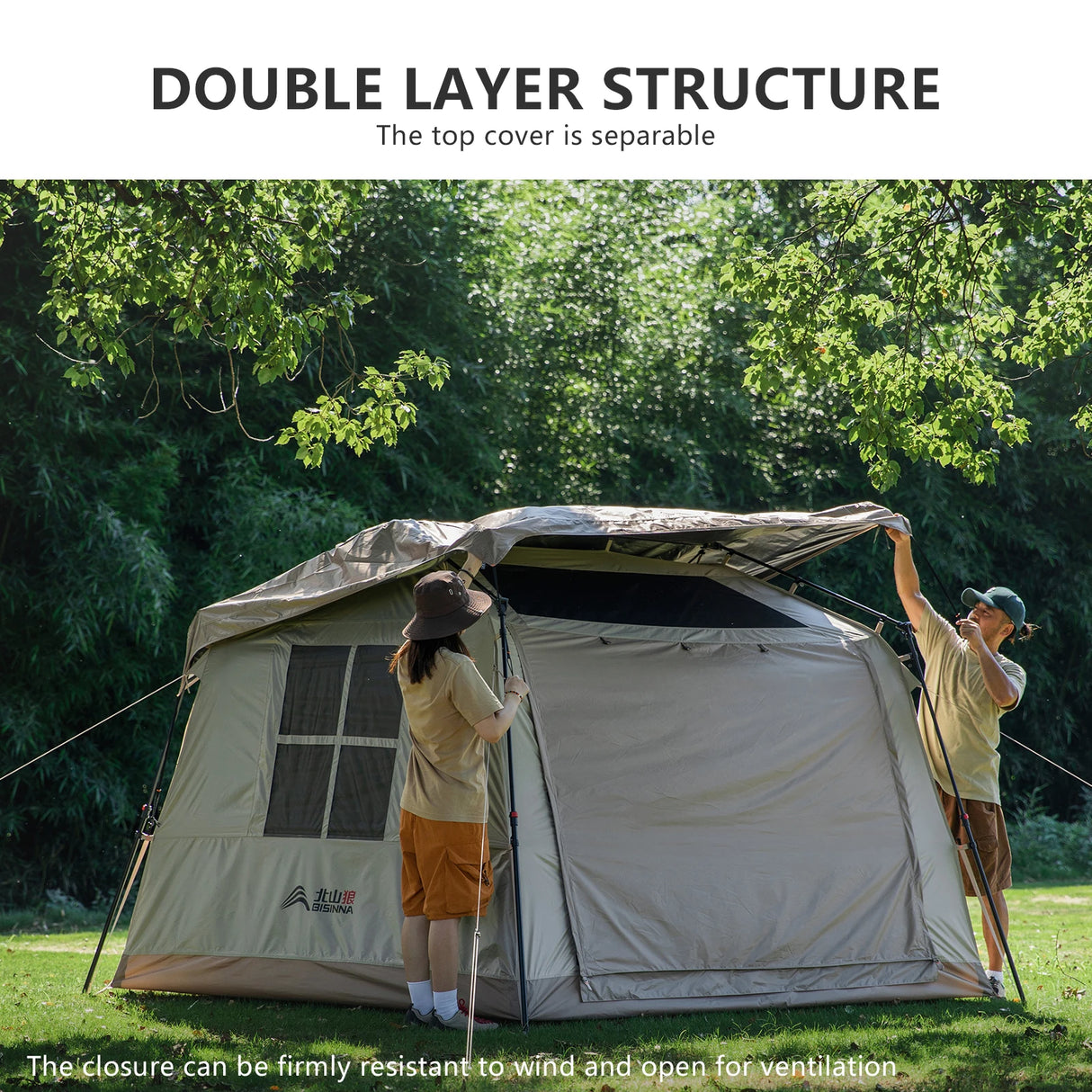 Two campers lifting the separate top cover onto the pitched cabin tent, showing how it detaches.
