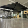 Black free-standing awning opened indoors, showing the fan-shaped canopy and support legs
