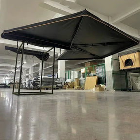 Black free-standing awning opened indoors, showing the fan-shaped canopy and support legs