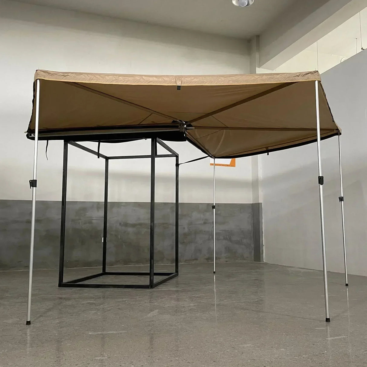 Khaki free-standing awning on poles, shown from the front against a plain wall