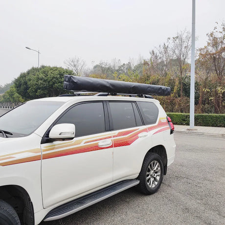 Closed awning in its black cover mounted along a white wagon's roof rack