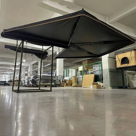Black awning displayed on an indoor test frame, canopy seen from below