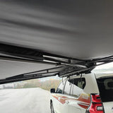 Underside of the grey canopy and folding arms above a white wagon
