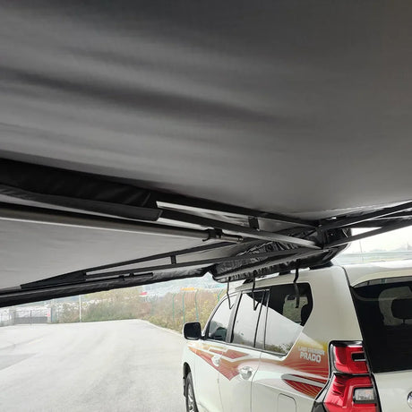 Underside of the grey canopy and folding arms above a white wagon