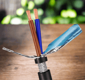 Two-core shielded cable on a timber bench, brown and blue cores exposed above the foil wrap and braided screen.