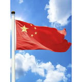 Chinese flag in printed polyester flying from a pole against blue sky: five yellow stars on red