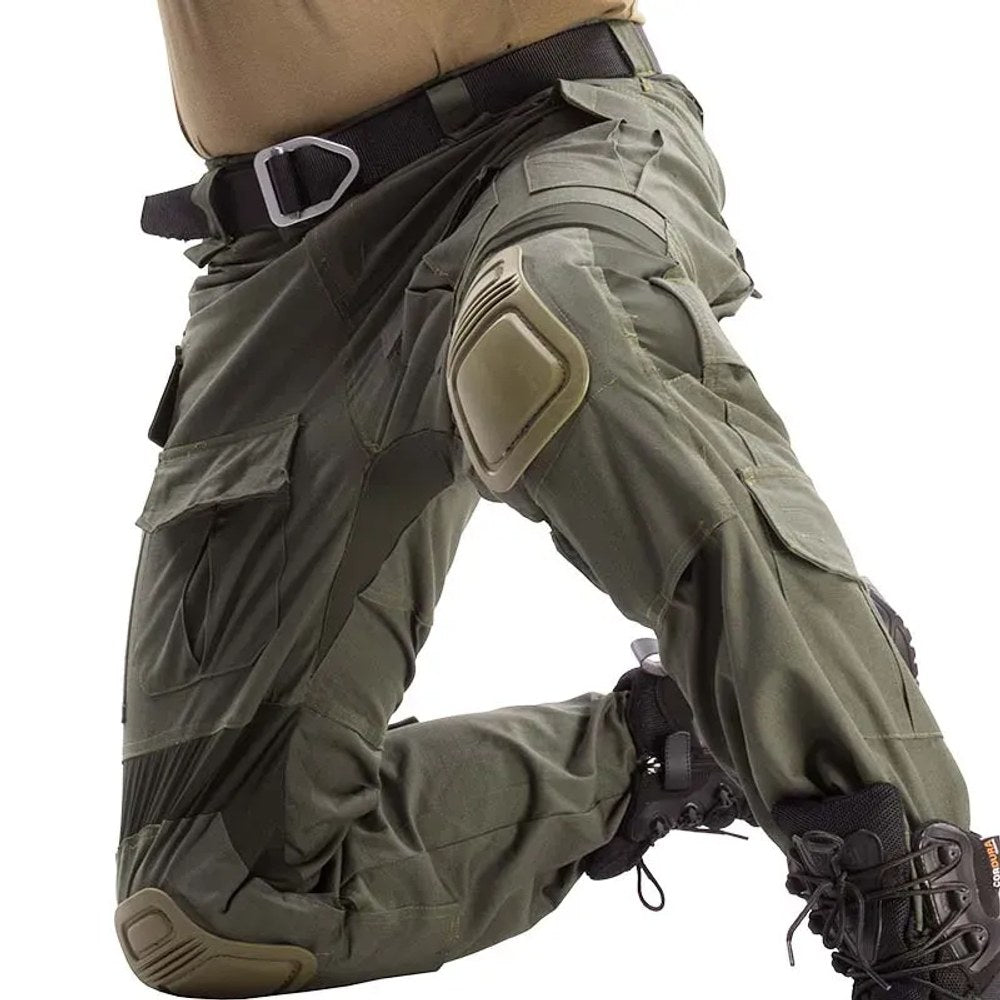 Olive green combat-cut trousers worn kneeling, knee pads in place