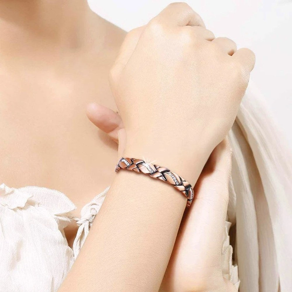 Slim X-link copper bracelet worn on a woman's wrist