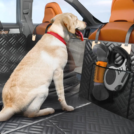 Labrador sitting on the black quilted rear seat cover beside the mesh window, a side pocket holding a toy and a lead