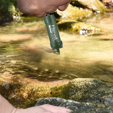 Hiker drinking straight from a shallow creek through a green filter straw