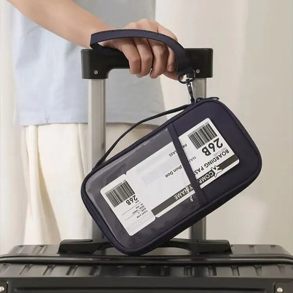 Navy wallet with a clear front pocket strapped to a suitcase handle, a luggage tag showing through