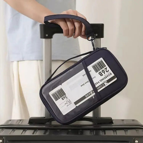 Navy wallet with a clear front pocket strapped to a suitcase handle, a luggage tag showing through