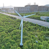 Drone view of a G Type horizontal wind turbine on a ground mast with service ladder rungs, standing in open scrub - representative family photo
