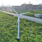 Drone view of a G Type horizontal wind turbine on a ground mast with service ladder rungs, standing in open scrub - representative family photo