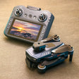 GT8 folding drone, folded, beside its remote control with a built-in screen, on a table