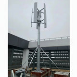 Five-blade H12 vertical axis wind turbine pole-mounted on a building rooftop under an overcast sky - representative family photo