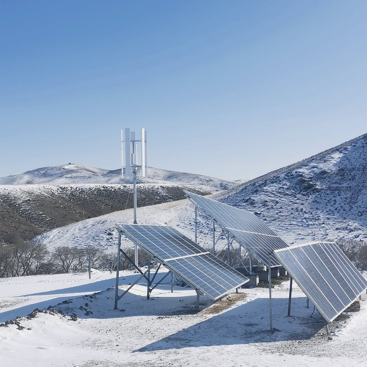 H2000 wind turbine beside ground-mounted solar panels on a snowy hillside