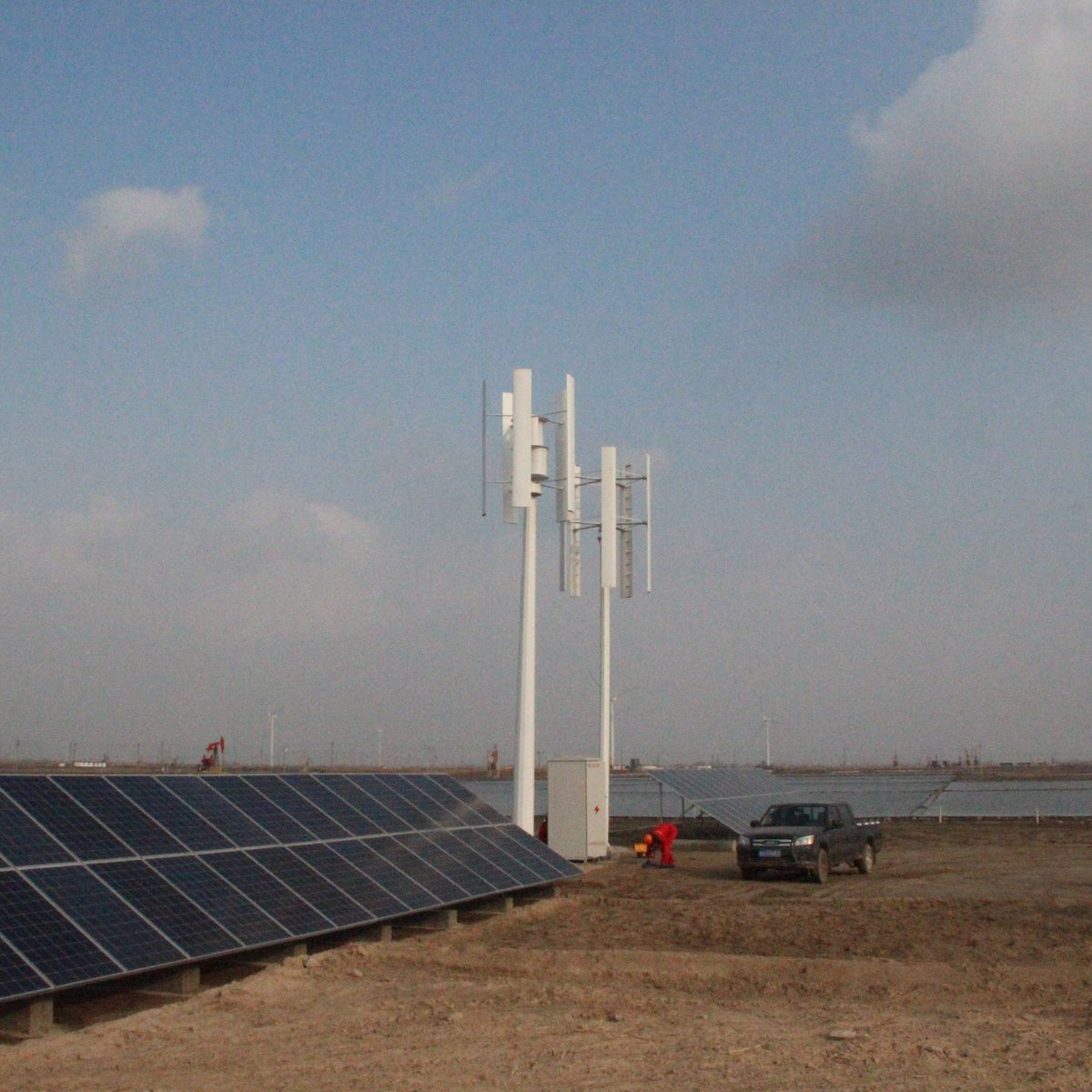 H2000 vertical wind turbines standing over a row of solar panels