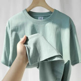 Mint green heavy cotton tee held up to show the thickness