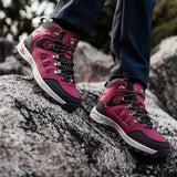 Rose red hiking boots worn with dark trousers, climbing over granite rock