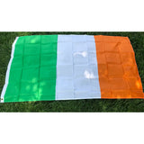 Irish flag in printed polyester laid flat on grass: green, white and orange, white header strip at left