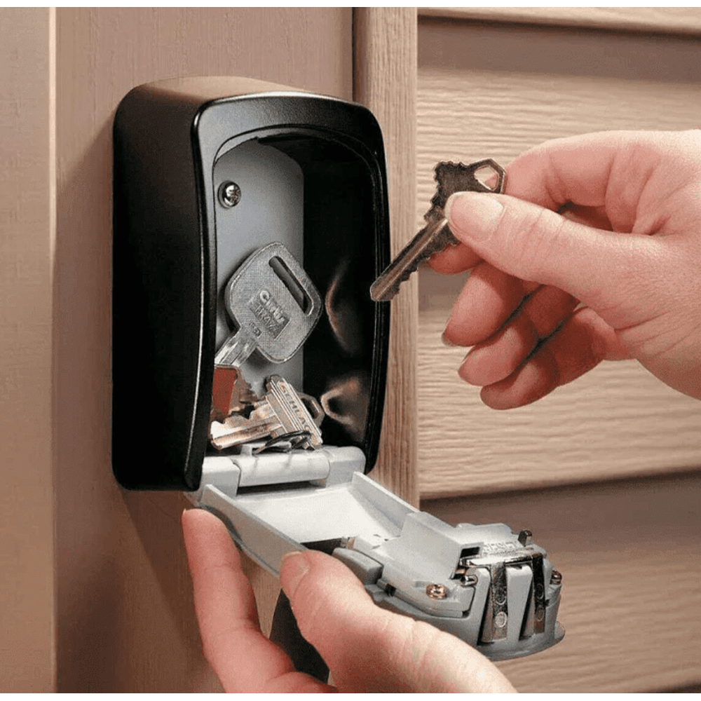 Wall mount key safe open on a timber wall, a hand lifting a key off the hook inside