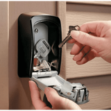 Wall mount key safe open on a timber wall, a hand lifting a key off the hook inside
