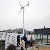 Installation crew in hard hats raising a horizontal-axis wind turbine on a tall mast — representative L-series family photo