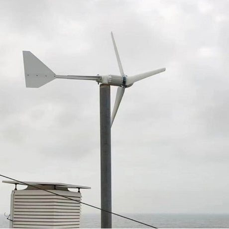 L-series wind turbine pole-mounted beside a weather station enclosure on an ocean-front deck under a grey sky - representative family photo