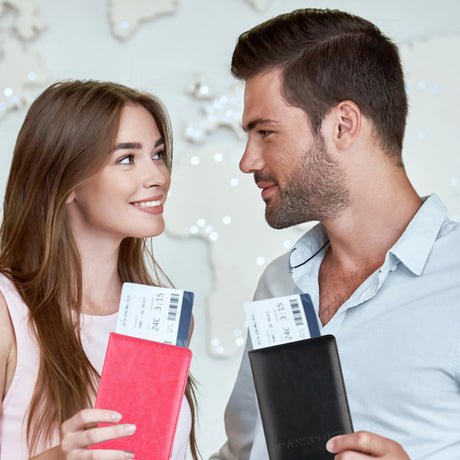 Two travellers holding rose red and black passport covers with boarding passes sticking out