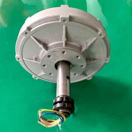 Silver generator face-on, showing the bolt-hole flange around the shaft and the ribbed aluminium case