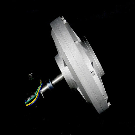 Side view of the silver generator on a black background, showing the flat disc-shaped case and the shaft with leads