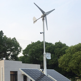 M-series turbine above two solar panels on a rooftop pole mount with CCTV camera and antennas - a wind-solar hybrid setup