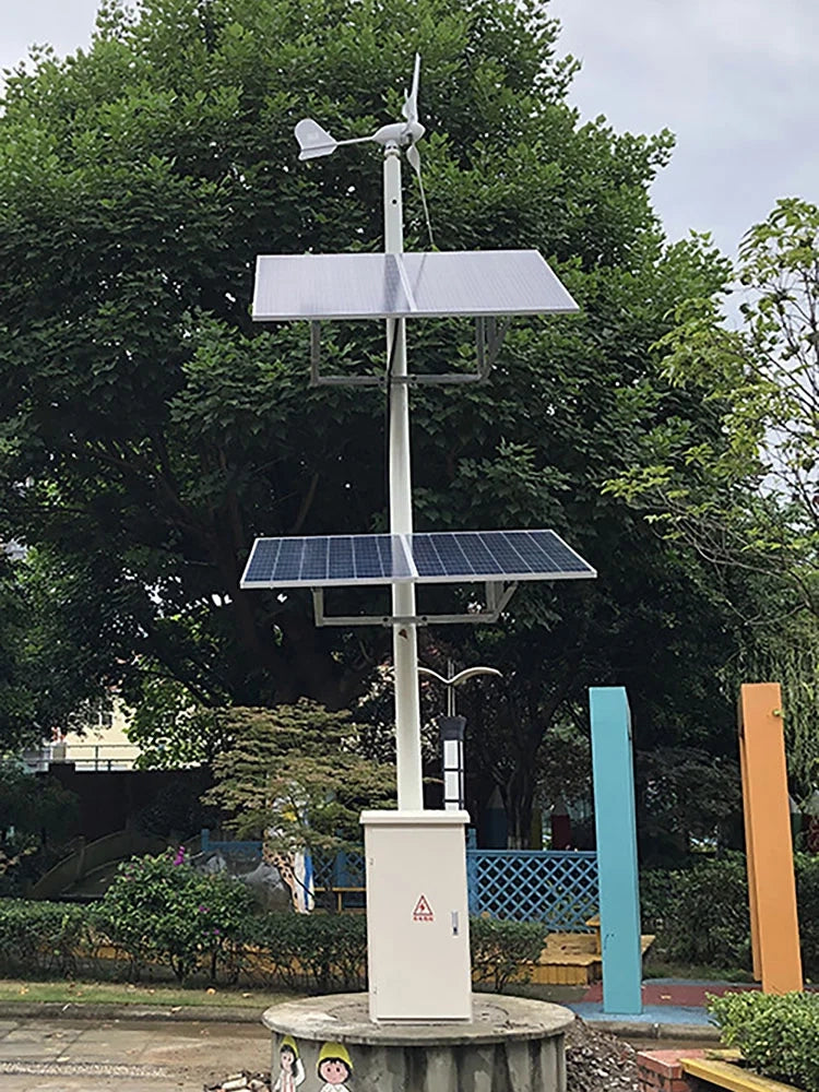 Wind-solar street pole in a park: a small horizontal turbine on top, two tiers of solar panels, LED street lamp and control cabinet on a concrete plinth