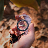 Clear baseplate compass with a degree dial and black cord lanyard held in an open hand